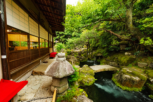 This is a photograph of the exterior of a restaurant in a traditional Japanese building with a koi pond and garden landscaped on the outside in Kyoto, Japan.
