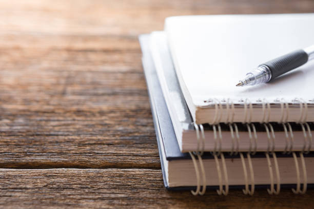 istock Selective focus of Pen, notebook on the wooden table and copy space with sunlight 1183257214