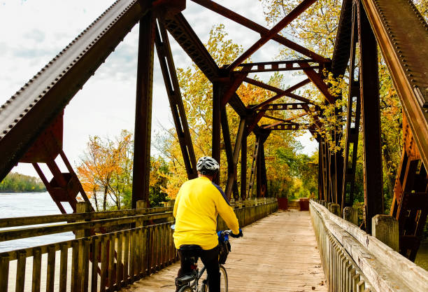 Photo of Senior male bicyclist riding on old metal bridge in autumn