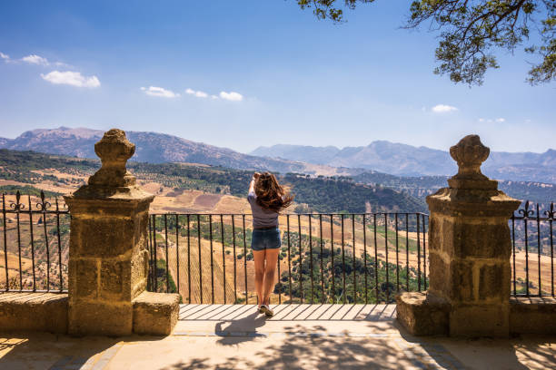 Woman taking photo from the mountaintop in Alameda del Tajo park in Ronda, Spain stock photo