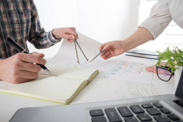 istock Architects working on blueprint, real estate project. Architect workplace - architectural project, blueprints, ruler, calculator, laptop and divider compass. Construction concept. Engineering tools. 1183288456