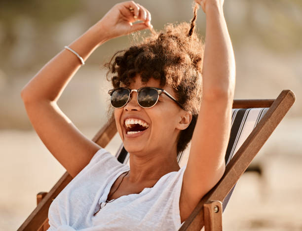 Summer, the official happy season Shot of a happy young woman enjoying a summer’s day at the beach deckchair stock pictures, royalty-free photos & images