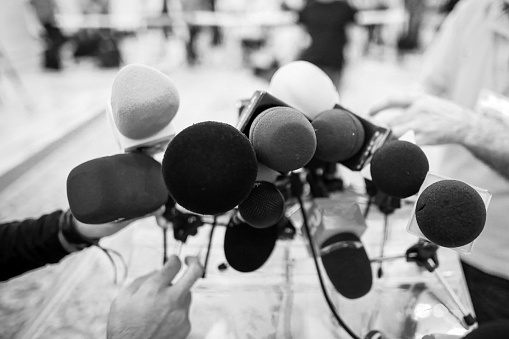 Shallow depth of field image with microphones installed by journalists at a press conference - politician point of view - black and white