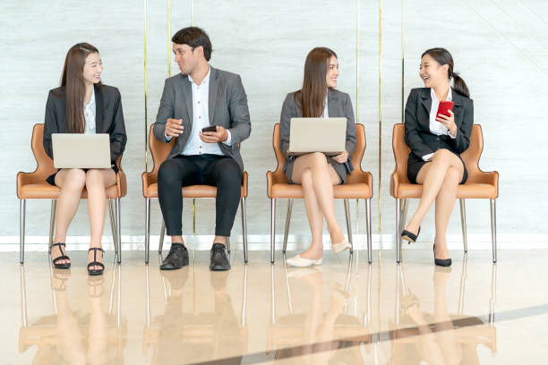 groupe de candidats d'affaires asiatiques personnes assises dans une rangée, attendant en ligne pour l'entrevue d'emploi - unemployment waiting in line waiting room interview photos et images de collection