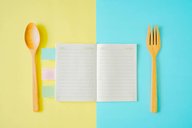 istock opened note book with wooden spoon and fork on yellow and blue paper background 1183297470