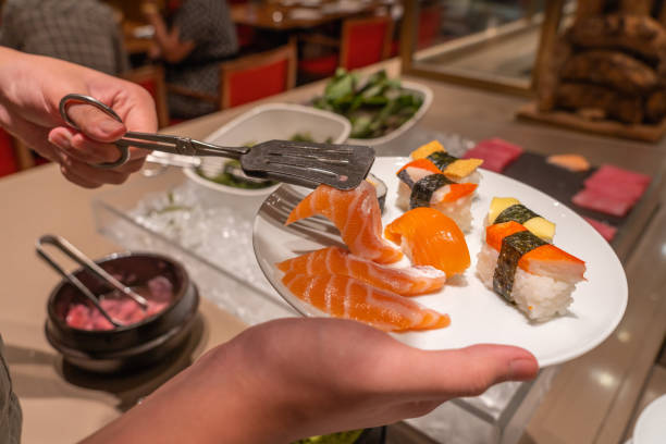 istock Human using tongs picking fresh sashimi and sushi in restaurant 1183298392