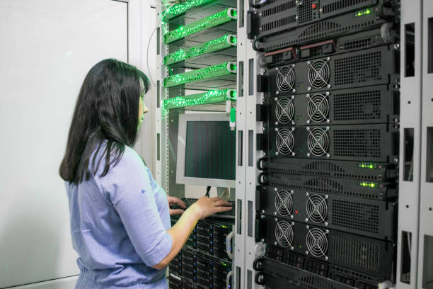istock A female programmer is working in a server room. The girl is standing next to the computer racks of the data center. The administrator looks at the monitor with network settings. 1183301772