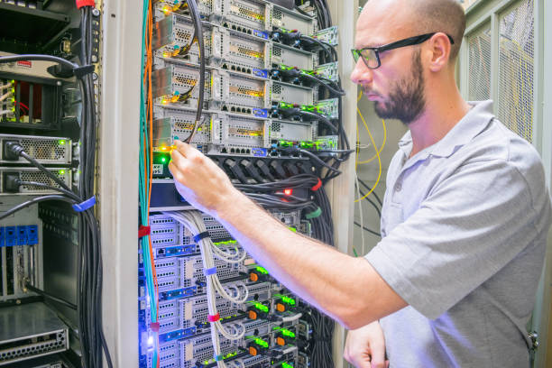 システム管理者は、データセンターで作業します。コンピュータ機器を扱う技術者の肖像画。ネットワークエンジニアがサーバールームラックの電源ケーブルを切り替える - messy network server cable computer ストックフォトと画像