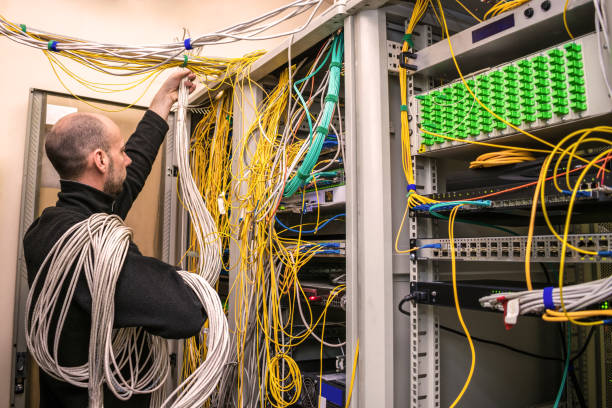 istock A communication specialist with hand-wound wires works in the server room. A man wrapped in cables is laying new communication lines in a data center. A technician lays communications in a data center. 1183302105