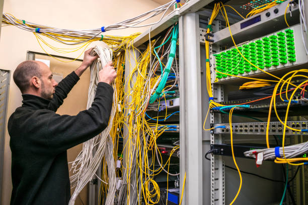 istock The system administrator is laying new cable communications in server racks. The man switches the wires to the cross panel of the data center. The technician works in the server room. 1183302116