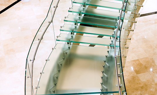 the edge of the glued glass of the railing covered by a U-shaped strip. transparent fillings of the railing made of shiny stainless steel tube bent. step into the building, polished