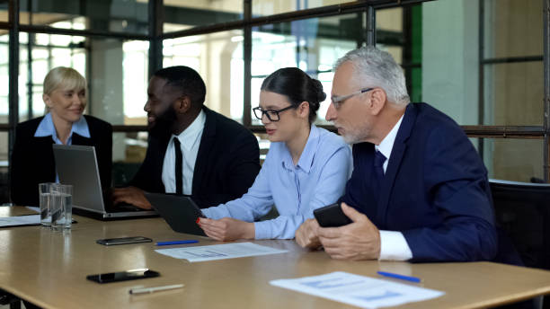 istock Company colleagues discussing news in office, using modern gadgets, teamwork 1183304349