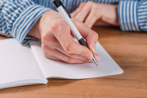 istock Beautiful Female hands write pen in a notebook of tasks and goals to work on a  table 1183304376