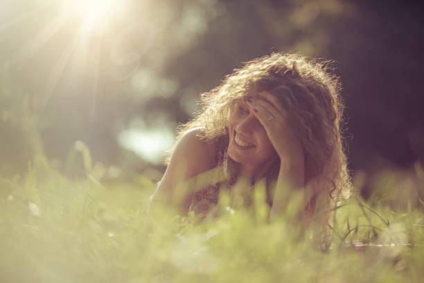 Woman is beautiful with smile. Girl lying on grass.