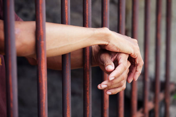 istock close up of hands in jail background 1183304693