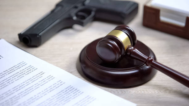 Gun on table, gavel lying on sound block, illegal use weapon, court hearing stock photo
