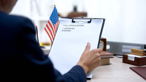 istock Female immigration inspector denying visa application, american flag on table 1183307719
