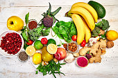 Selection of food rich in antioxidants and vitamins and mineral  sources, vegan food  on white wooden background. Healthy balanced dieting concept, ingredients for cooking. Top view, flat lay, copy space.