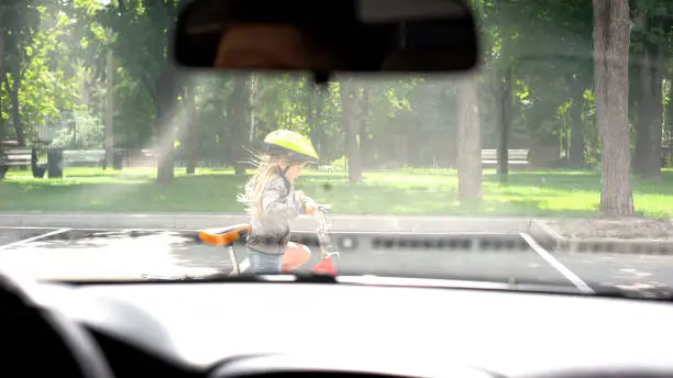 Photo of Kid riding bicycle in street, attentive driver stopping car, accident prevention