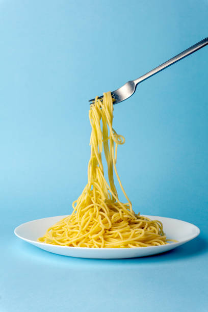 istock Spaghetti pasta with a fork on a white plate on a blue background. Creative, minimal concept 1183311800
