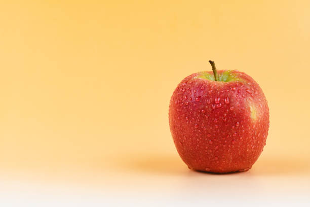 fuji apple con gocce d'acqua isolate su sfondo giallo - apple gala apple fuji apple fruit foto e immagini stock