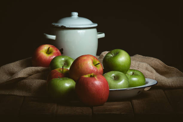 green and red apples on wooden table with small casserole
