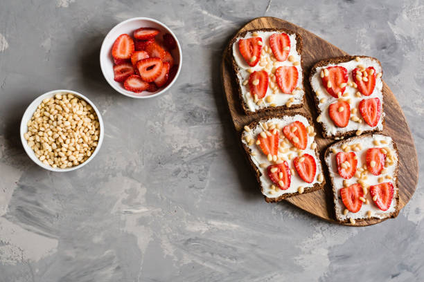 istock Healthy breakfast. Black bread with strawberry, pine nuts and cheese on gray concrete background. Authentic lifestyle image. Flat Lay, Copy space, top view, overhead, mockup, template. Food concept 1183321905