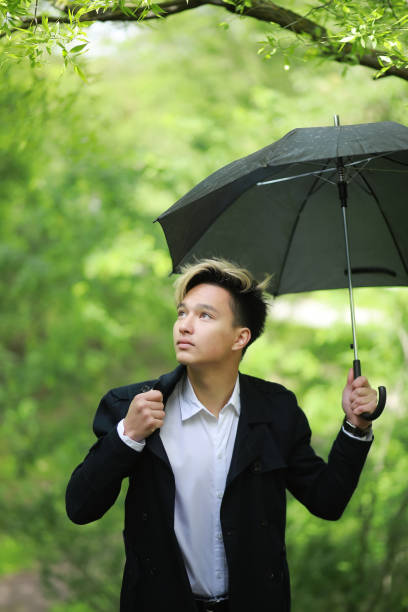 istock Spring rainy weather and a young man with an umbrella 1183323140