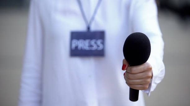 istock Journalist with press id proposing microphone for interview, television news 1183325187