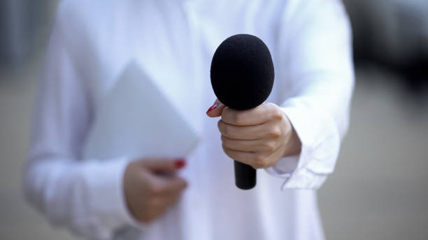 istock Female journalist with notebook proposing microphone, interviewing celebrity 1183325194