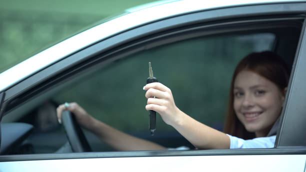istock Cheerful girl showing automobile key sitting on driver seat, test-drive, gift 1183325607