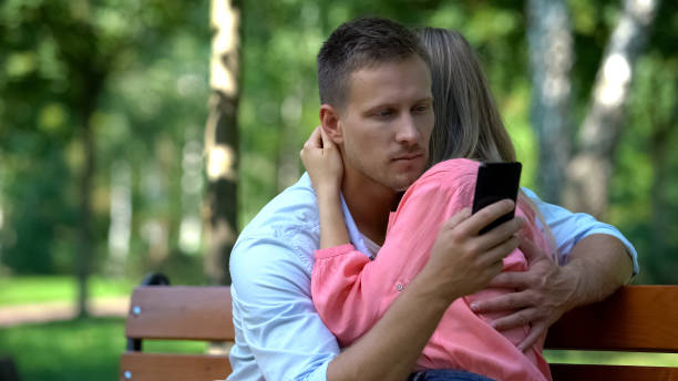 istock Boyfriend texting message another woman while hugging girlfriend, betrayal 1183326085