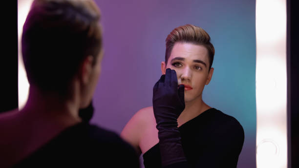 istock Man looking at half-face makeup in mirror, accepting female inner self 1183326910