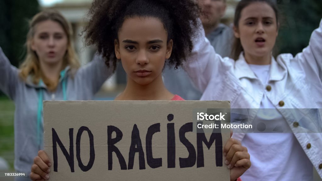 Afroamerican girl holding No racism sign, activists chanting Human rights slogan Anti-racism Stock Photo
