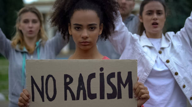 Afroamerican girl holding No racism sign, activists chanting Human rights slogan Afroamerican girl holding No racism sign, activists chanting Human rights slogan social justice concept photos stock pictures, royalty-free photos & images