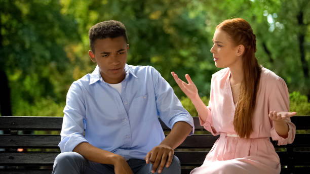 istock Multiethnic couple arguing sitting on bench in park, jealousy, misunderstanding 1183329147