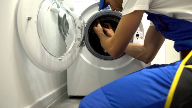istock Foreman in uniform repairing washing machine using screwdriver, maintenance 1183329276