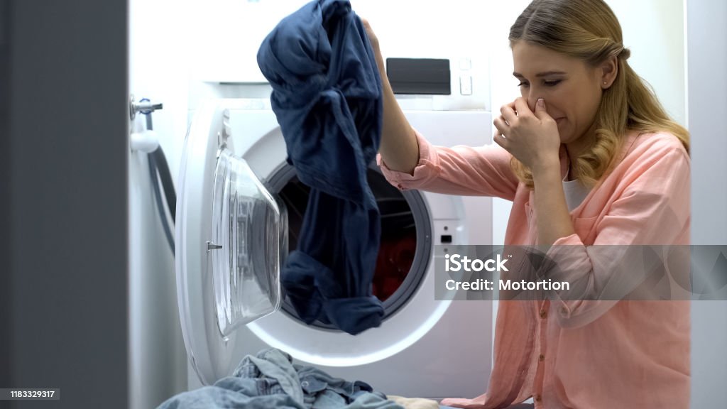 Woman closing nose from stinky clothes after washing, low-quality soap-powder Unpleasant Smell Stock Photo