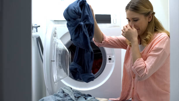Woman closing nose from stinky clothes after washing, low-quality soap-powder stock photo