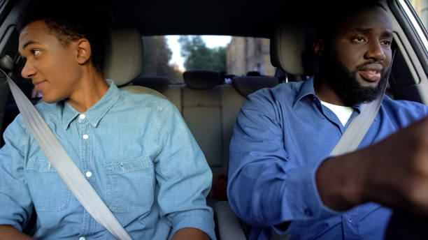 istock Father and son driving in automobile, guy looking in window, misunderstanding 1183329629