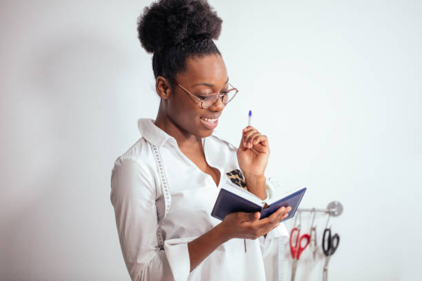 istock african girl seamstress making notes at notebook. designer drawing sketches 1183330131