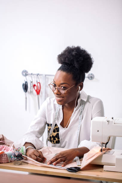 istock smiling seamstress looking at camera with sewing machine 1183330206