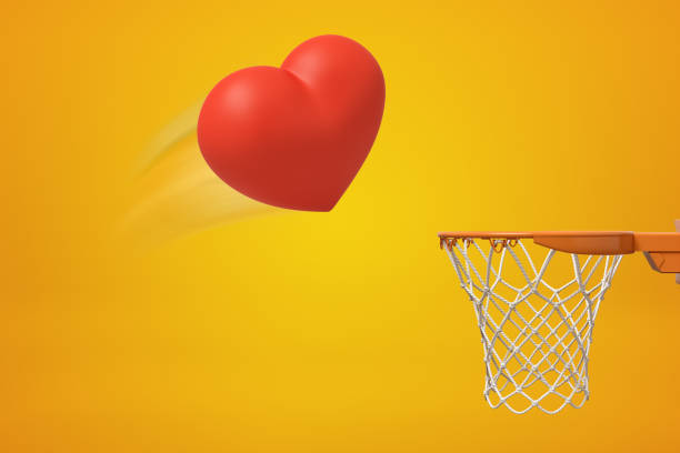 3d rendering of red heart flying into basketball hoop on yellow background 3d rendering of red heart flying into basketball hoop on yellow background. Digital art. Feelings and emotions. Love and sports. heart shaped basketball stock pictures, royalty-free photos & images