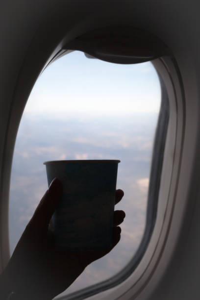 istock Hand holding a coffee cup in front of an airplane window 1183336940