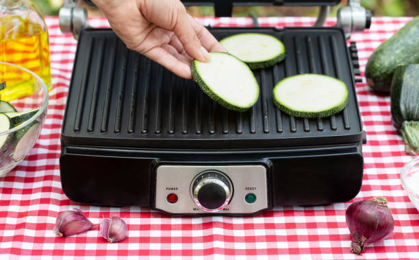 istock Female hand puts sliced zucchini on grill 1183337504