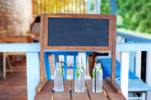 In the park on the green lawn a wooden counter with a lemonade. An adorable summer lemonade stand. Cooking homemade lemonade in the garden. Lemonade in a glass jar on a wooden stand in the open air