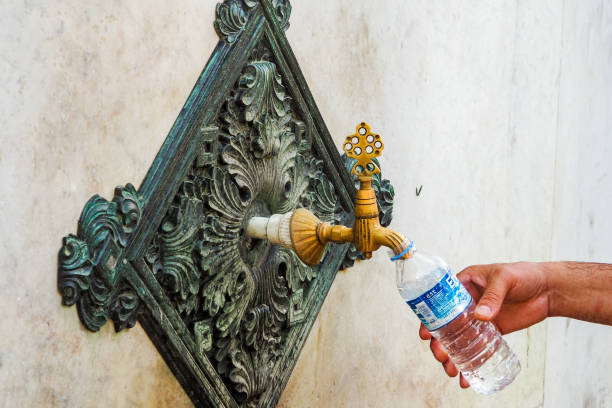 mano dell'uomo che riempie la bottiglia d'acqua dalla gru della fontana tedesca - istanbul people faucet turkey foto e immagini stock
