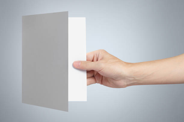 istock Hand holding a sheet of white paper on gray 1183340332