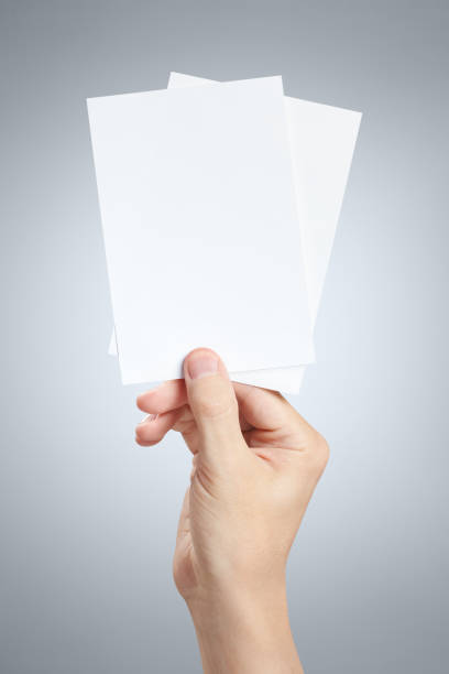istock Hand holding two small sheets of paper on gray 1183340363