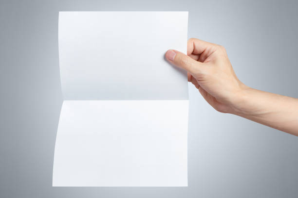 istock Hand holding a sheet of white paper on gray 1183340393